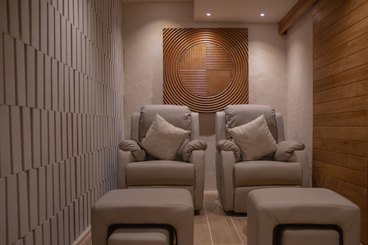 Un moderno espacio de spa con dos sillones reclinables y un panel de pared de madera.