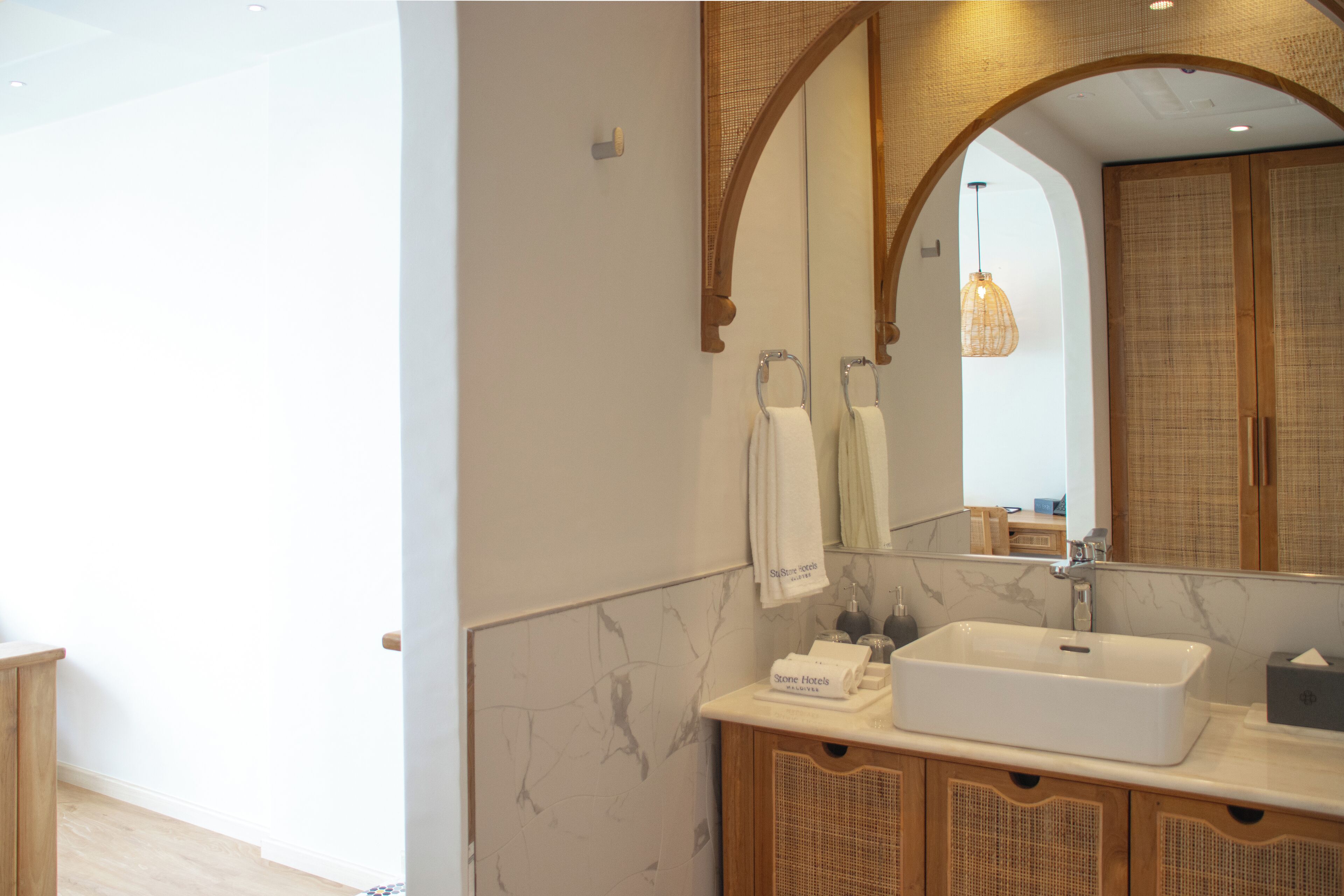 A modern bathroom with a large mirror, a white sink, and wooden cabinets.