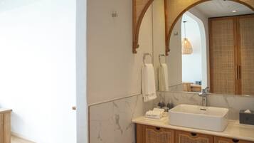 A modern bathroom with a large mirror, a white sink, and wooden cabinets.