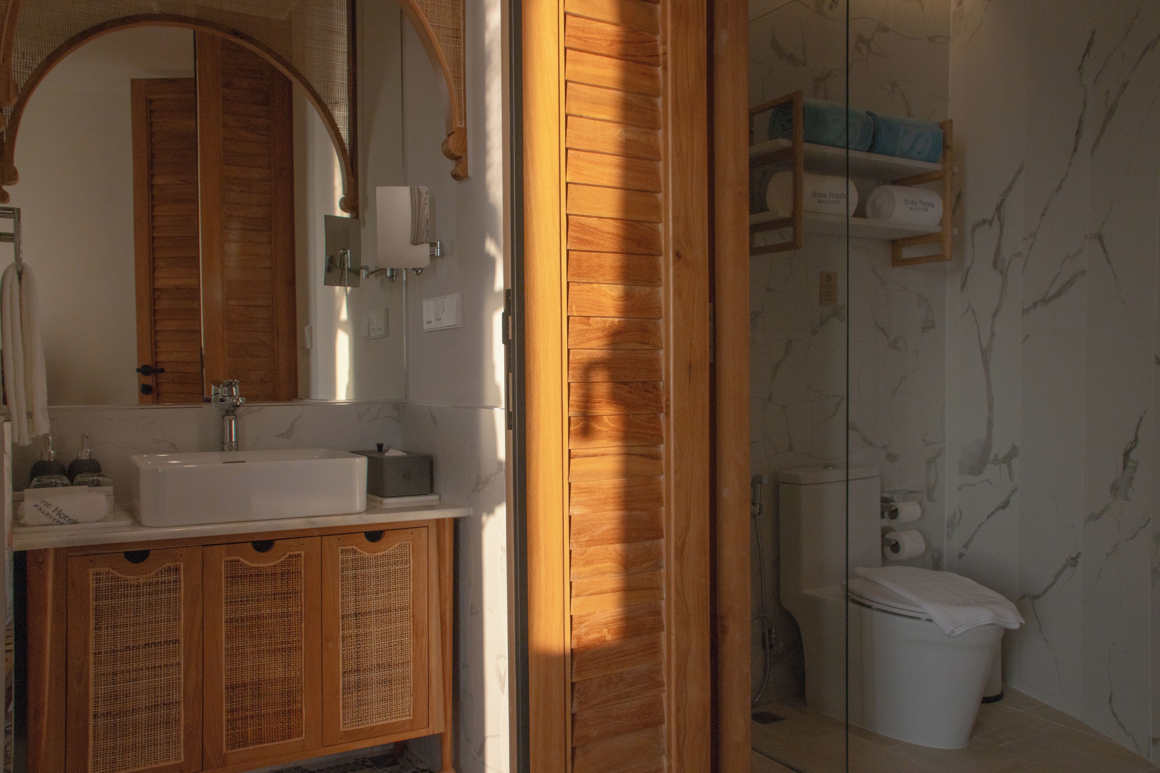 A bathroom with a wooden vanity, a sink, and a toilet.