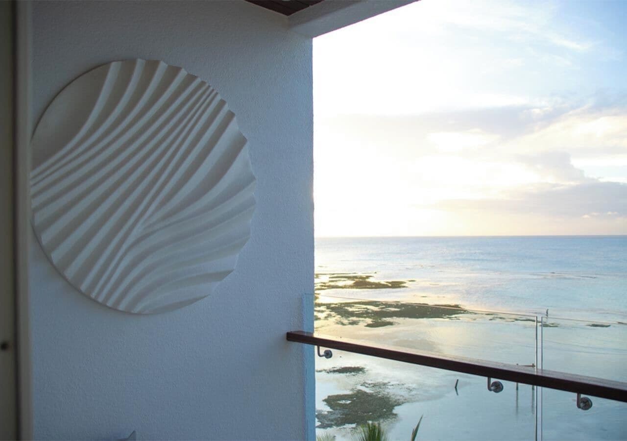 A balcony with a glass railing overlooking a beach.