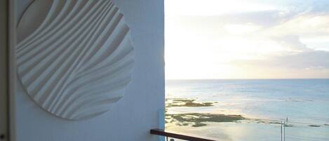 A balcony with a glass railing overlooking a beach.