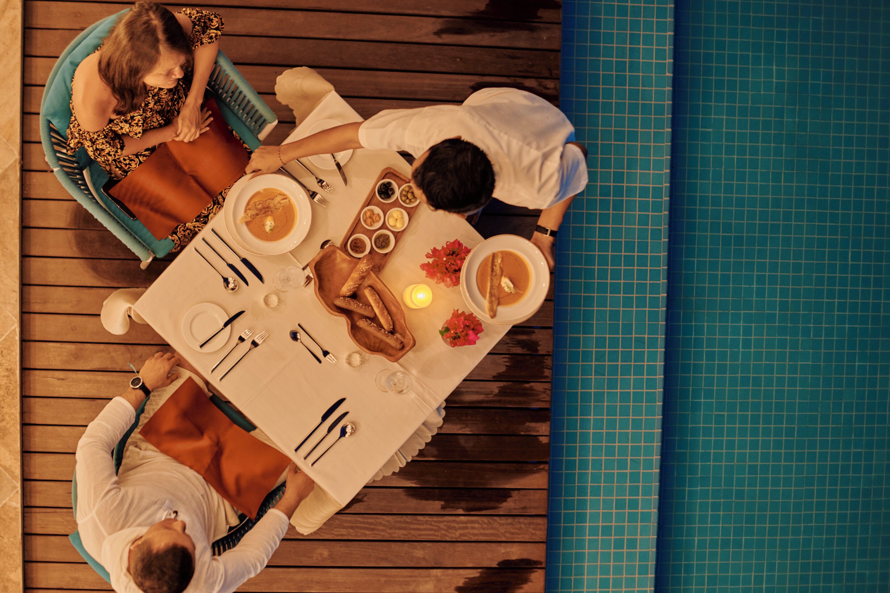 A dining table set for four people with a pool in the background.