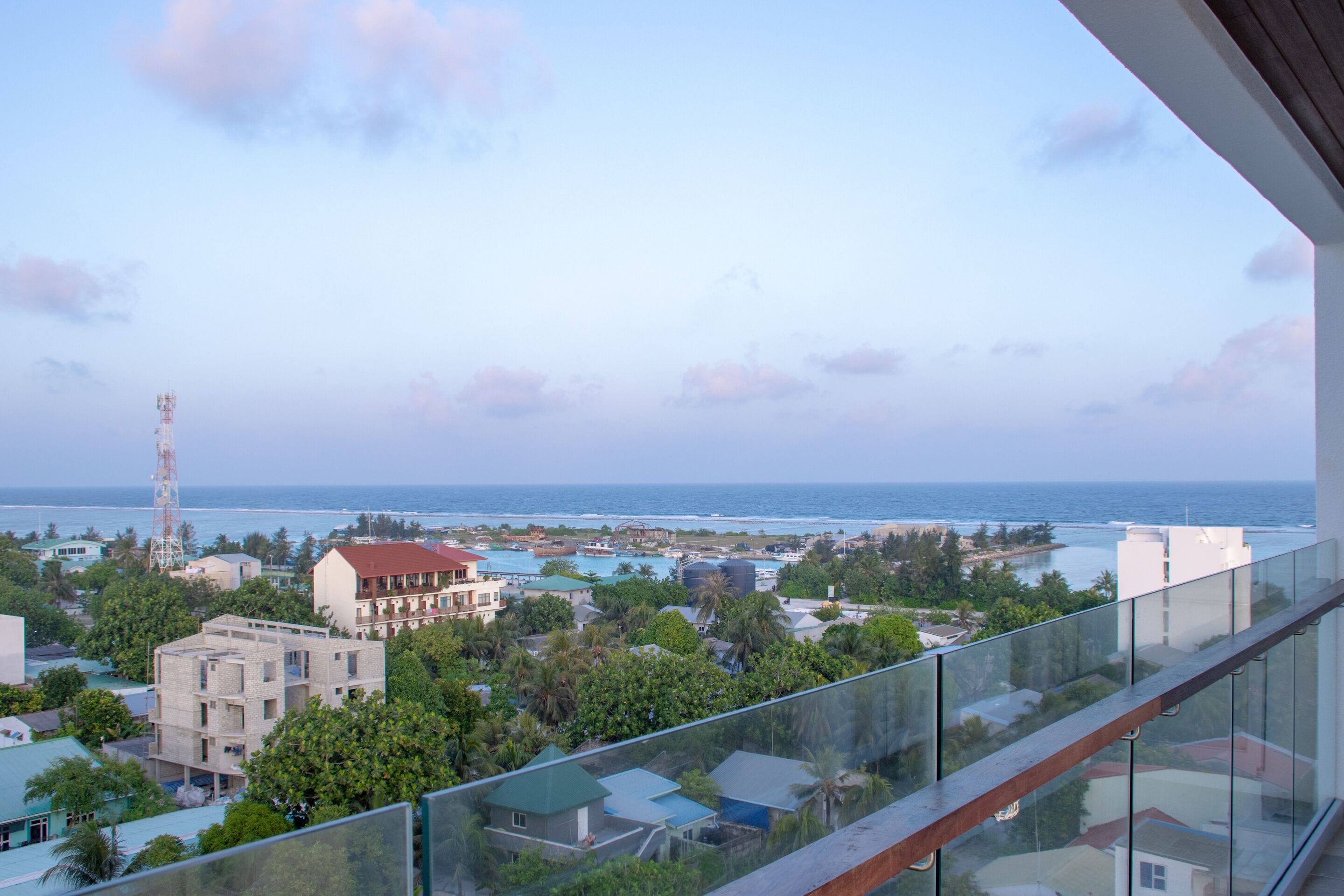 A balcony with a clear view of the ocean and surrounding buildings.