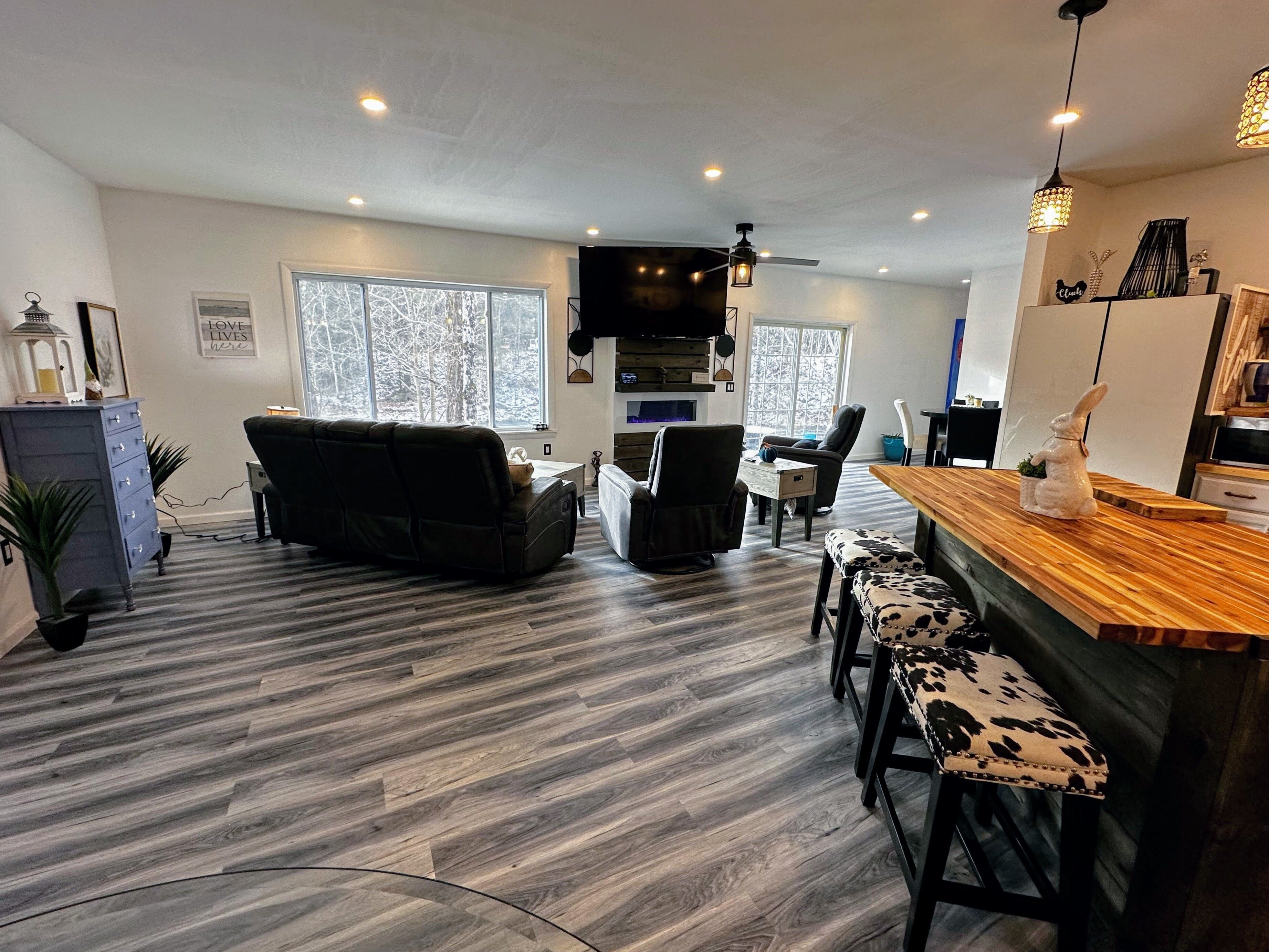 A modern living room with a sofa, chairs, a wooden coffee table, and a bar area with stools.