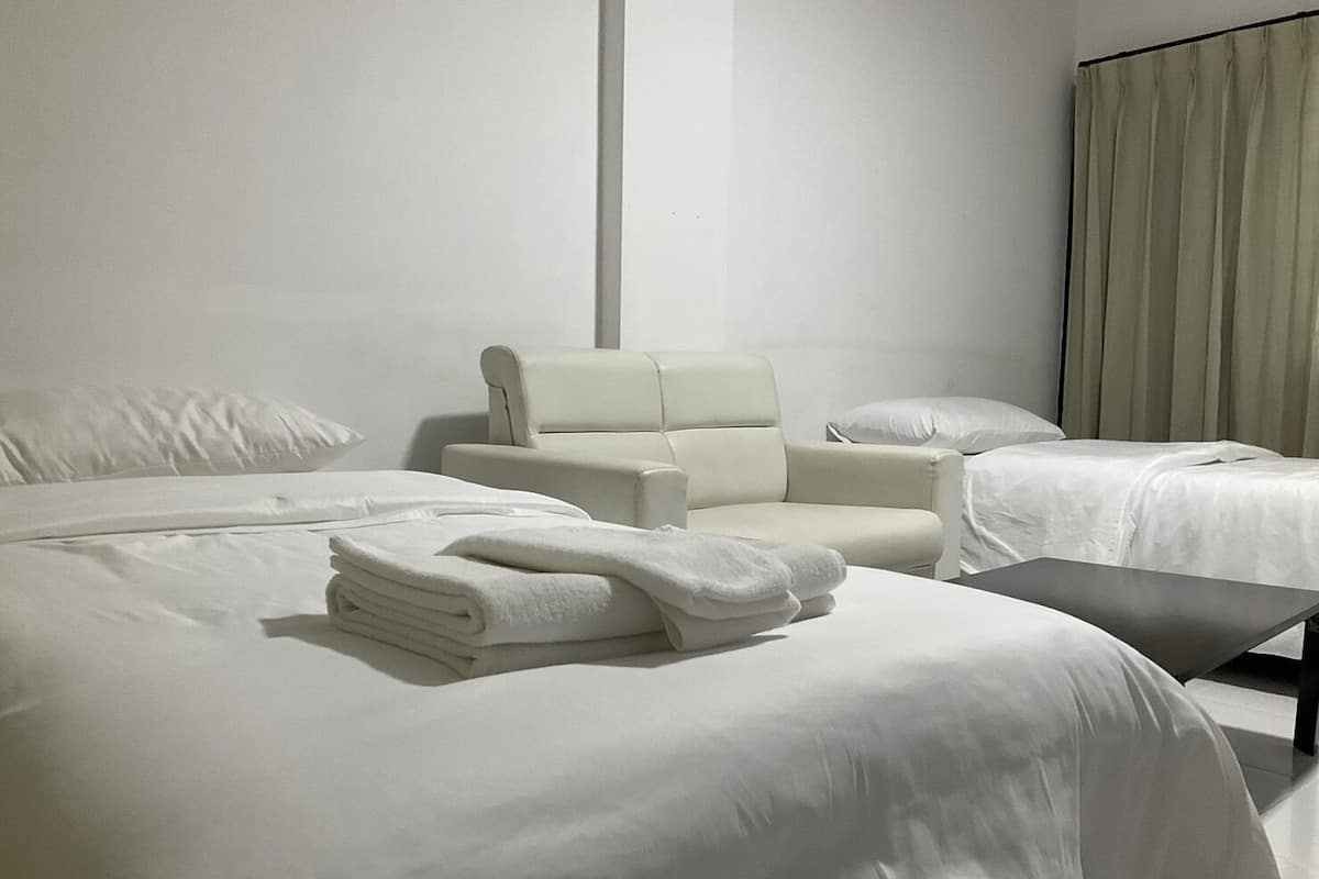 Habitación de hotel con dos camas, una silla y una pequeña mesa.
