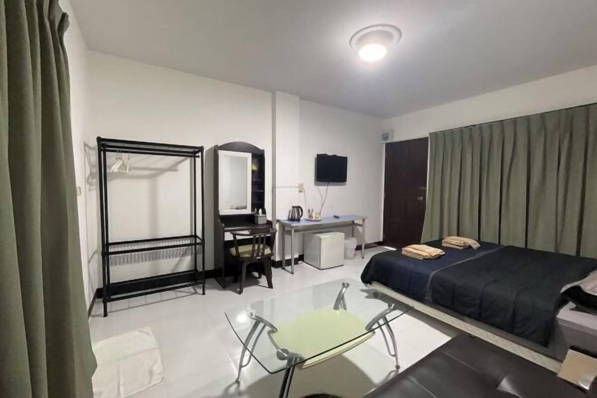 Una habitación de hotel con cama, escritorio, silla y espejo.