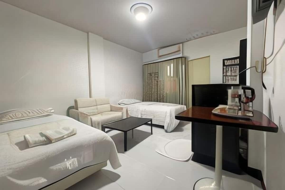Una habitación de hotel moderna con una cama, un sofá, una mesita y un televisor.