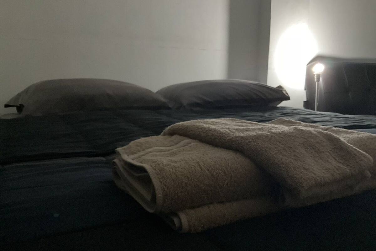 Una cama con una manta doblada y dos almohadas.