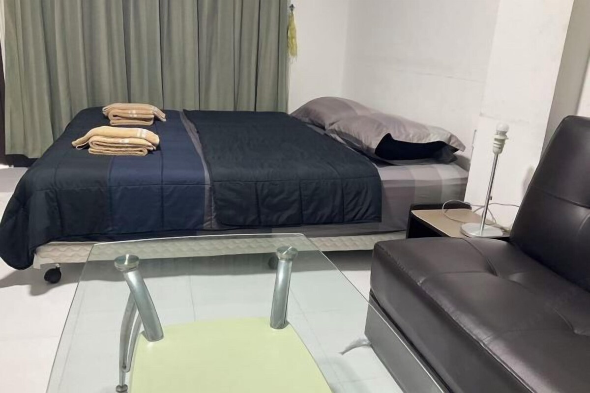 A hotel room with a bed, a sofa, a nightstand, and a lamp.