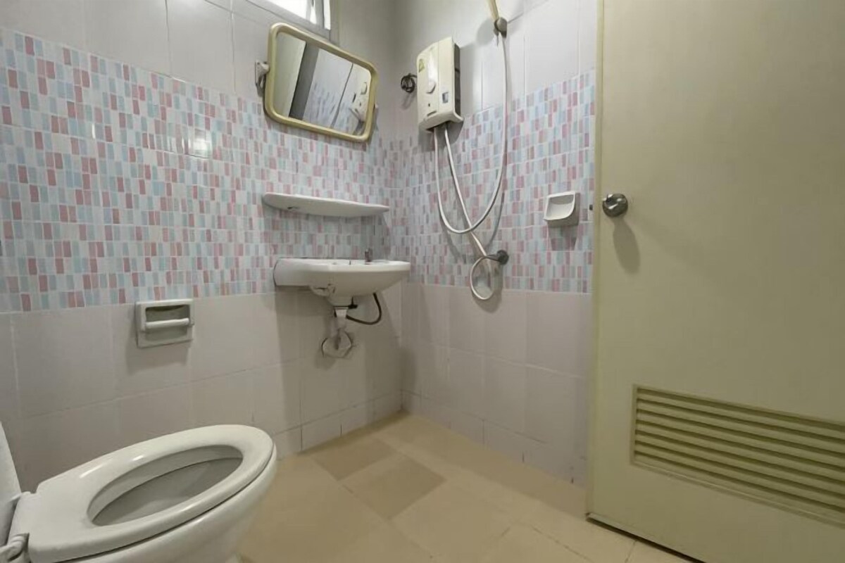 A bathroom with a toilet, sink, mirror, and shower.