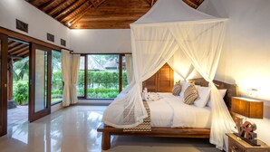 A spacious bedroom with a wooden ceiling, a large bed with a canopy, and a view of greenery outside. - Green Sari Private Villa (Ubud)