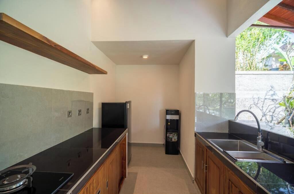 A compact kitchen with a black countertop, wooden cabinets, a built-in stove, and a sink.