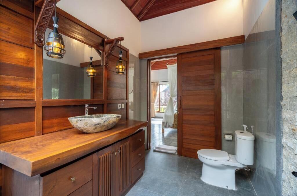 Une salle de bain avec un meuble-lavabo en bois, un grand miroir et un lavabo en pierre.