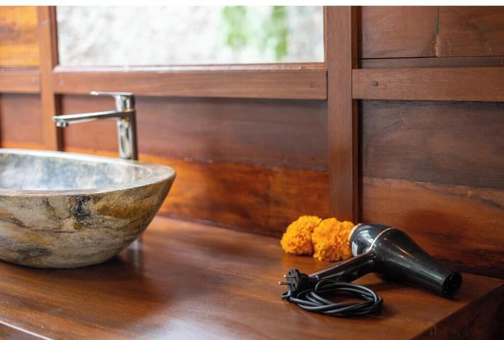 A wooden countertop with a marble sink, a hairdryer, and a power cord.