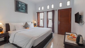 A bedroom with a large bed, bedside tables, a TV, and a door with windows. - Sekar Bali Homestay (Gianyar)