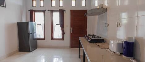 A kitchen with a refrigerator, a coffee maker, and a toaster on the counter.