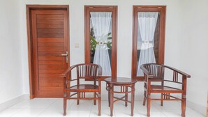 A room with a wooden door, two windows with sheer curtains, and a wooden table with two chairs. - Sekar Bali Homestay (Gianyar)