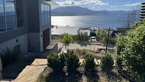 A modern two-story building with large windows overlooking a body of water and distant mountains. - Fusion House (Tranmere)
