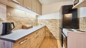 A modern kitchen with wooden cabinets, a stainless steel refrigerator, and a built-in microwave. - Chaloupka U lesa by Interhome (Harrachov)