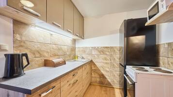 Een koelkast, een magnetron, een oven, kookgerei, borden en bestek