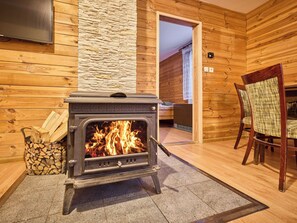Una estufa de leña en una habitación con paredes de madera y un muro de acento de piedra.