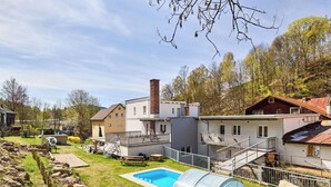 Ein Wohngebiet mit Swimmingpool, überdachter Terrasse und einer Treppe zu einem Balkon im zweiten Stock.