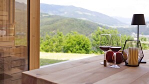 A wooden table with wine glasses, a candle, and apples. - Oberplunerhof Luxury Chalet Skyline with Mountain Views, Private Terraces & Shared Garden (Kiens)