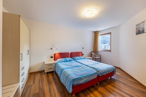 A bedroom with a bed, a wardrobe, a nightstand, a chair, and a window.