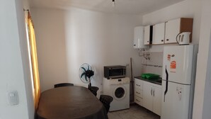 A compact kitchen with a washing machine, a microwave, and a refrigerator. - BellaVilla (Bell Ville)