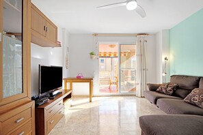 A living room with a television, sofa, and wooden cabinets. - Apartment 'Playa De Chilches' with Private Terrace and Balcony (Chilches)