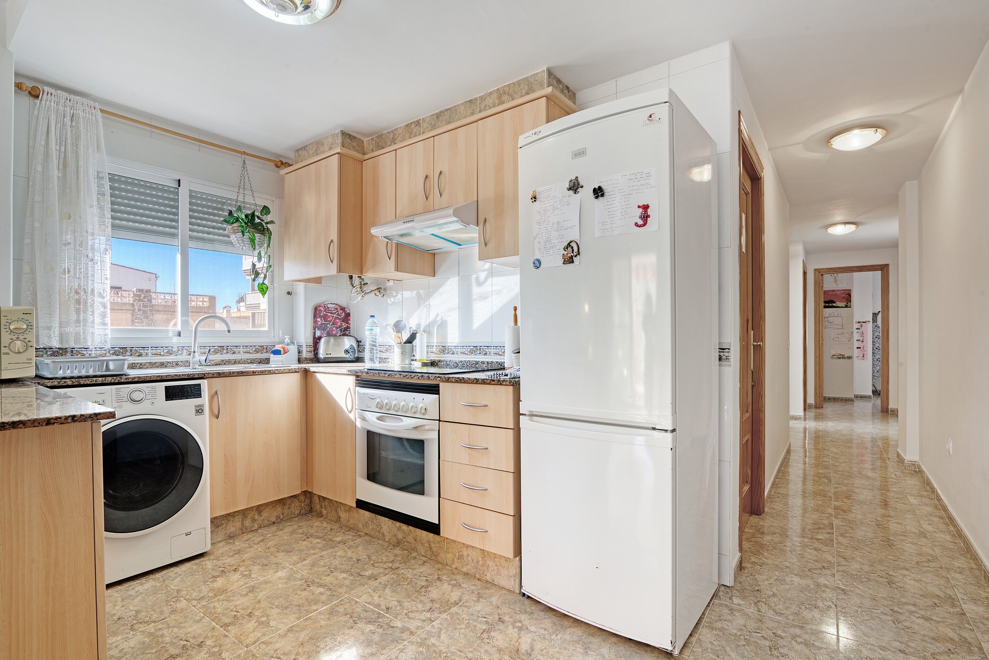 Eine Küche mit Waschmaschine, Backofen und Kühlschrank.