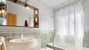 Ein Badezimmer mit Waschbecken, Spiegel, Toilette und Duschvorhang.