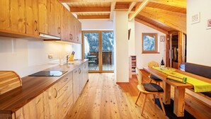 A wooden interior with a kitchen, dining area, and a view of the outdoors.