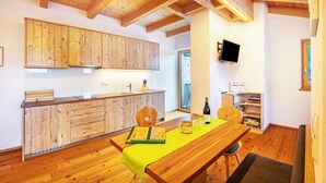 A wooden interior with a kitchen, dining area, and a TV mounted on the wall.