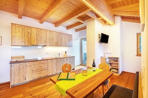 Un intérieur en bois comprenant une cuisine, un coin repas et un téléviseur fixé au mur.