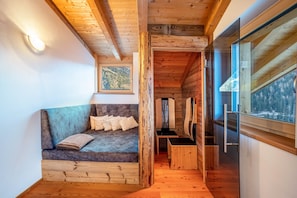 A wooden interior with a sofa, a framed picture, and a window with a view.