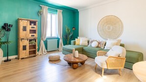 A living room with teal walls, a green sofa, a wooden cabinet, and a round table. - Milo Apt - Trastevere's Gem (Roma)