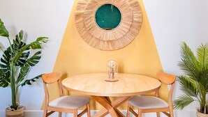 A round wooden table with four chairs, a wall-mounted circular mirror, and two potted plants. - Milo Apt - Trastevere's Gem (Roma)