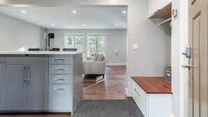 Une cuisine moderne avec des meubles gris, un plan de travail en bois et un four encastré.