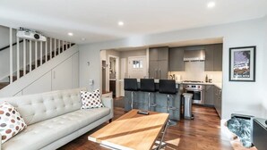Un salon moderne avec un canapé, une table basse et un escalier.