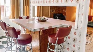 A dining area with a rectangular table, four red chairs, and a patterned wall.