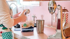 A kitchen with a stainless steel sink, a food processor, and a polka-dotted apron hanging on the counter.
