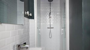 Une salle de bain moderne avec un lavabo blanc, un miroir et une douche à parois de verre.