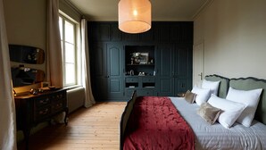 Une chambre à coucher avec un grand lit, une armoire en bois foncé, une commode et un luminaire suspendu.