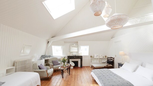 Ein geräumiges Schlafzimmer im Loft-Stil mit hohen Decken, einem Kamin, einem Esstisch und zwei Betten.