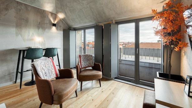 Una sala de estar moderna con dos sillones de cuero, una mesita y un ventanal con vistas a la ciudad.