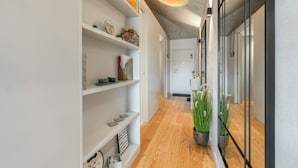 Un pasillo con estanterías blancas, suelo de madera y una planta.