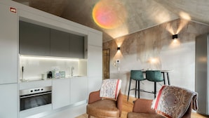 Una cocina moderna con electrodomésticos integrados, una zona de comedor con dos sillas y un aplique de pared.