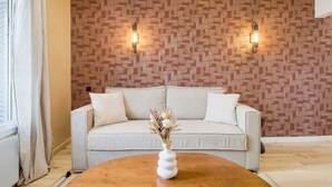 A modern living room with a patterned wall, a white sofa, and a wooden coffee table with a vase of dried flowers. - 11.Appart 4Pers#1 Bedroom #Père Lachaise #Nation (Paris)
